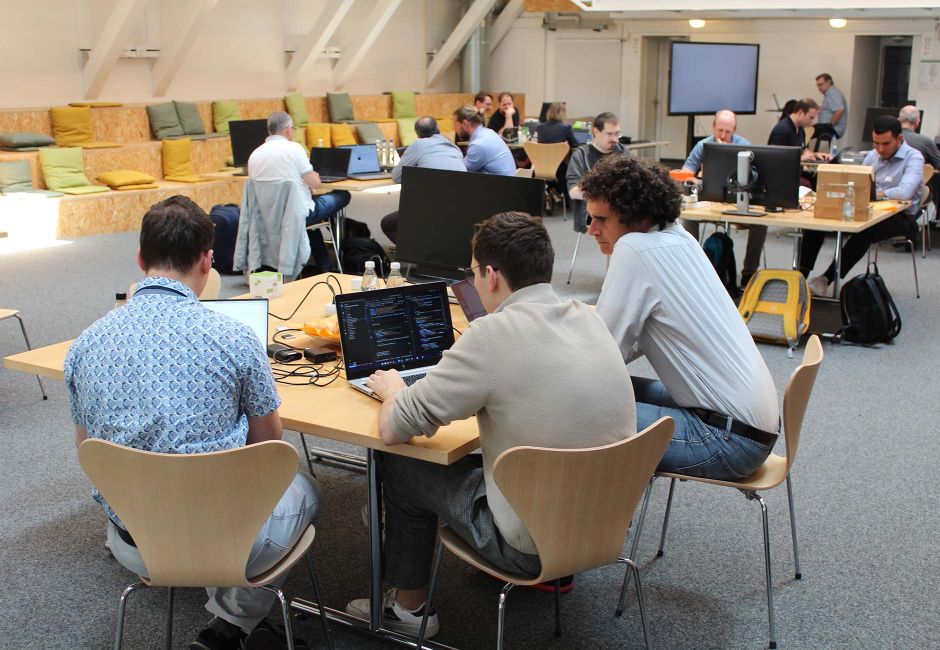 Eine Gruppe von Engineers im Fokus beim Hackathon in einer Halle Eine Gruppe von Engineers im Fokus beim Hackathon in einer Halle